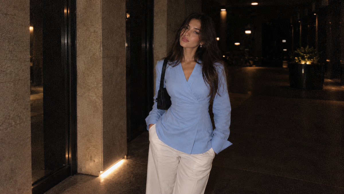 Blue Vellisse Top styled with white trousers, featuring a flattering wrap front and long sleeves
