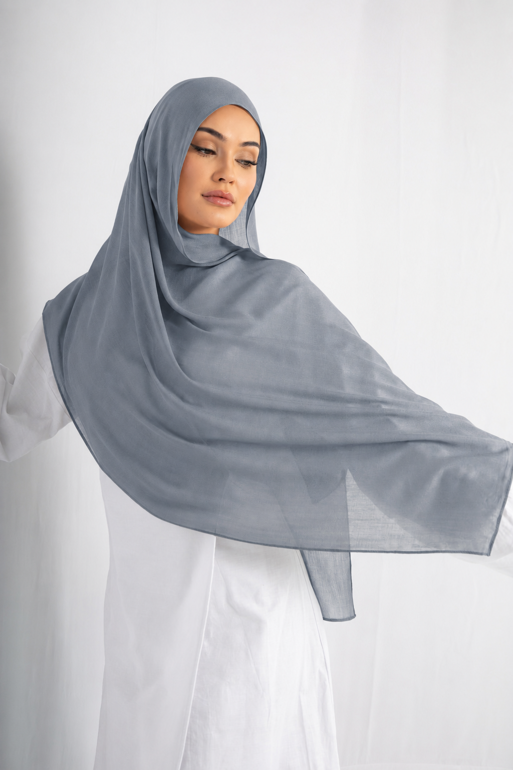 Woman wearing the Blue Haze modal hijab in a soft light blue shade, showcasing the lightweight fabric, flowing drape, and elegant modest style