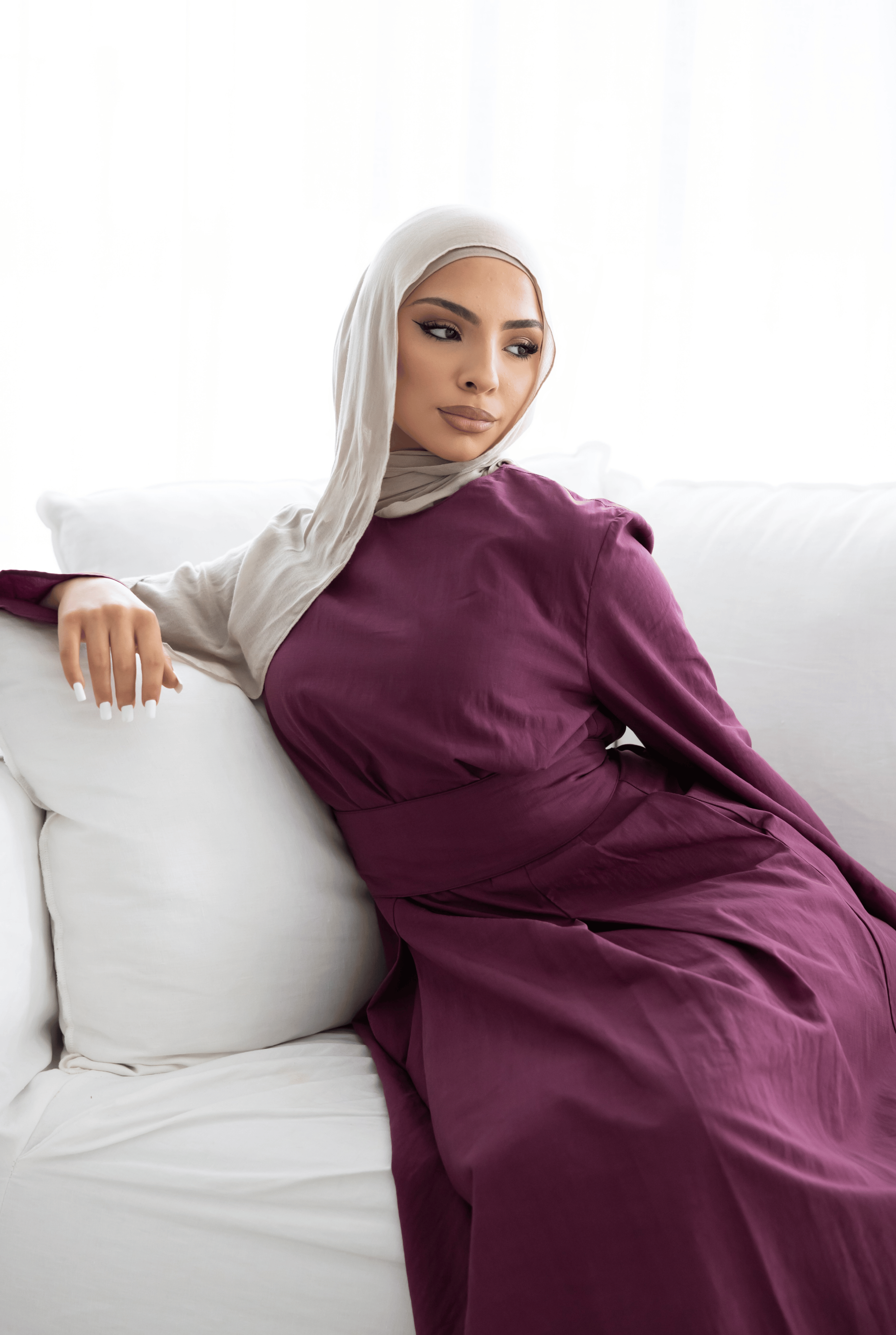 Lifestyle image of the Sorelle Belted Dress in plum, featuring a flowing full-length silhouette, matching waist belt, and elegant wide sleeves. Crafted from a breathable lyocell-linen blend, this modest dress offers effortless sophistication, comfort, and timeless style for everyday wear and special occasions.