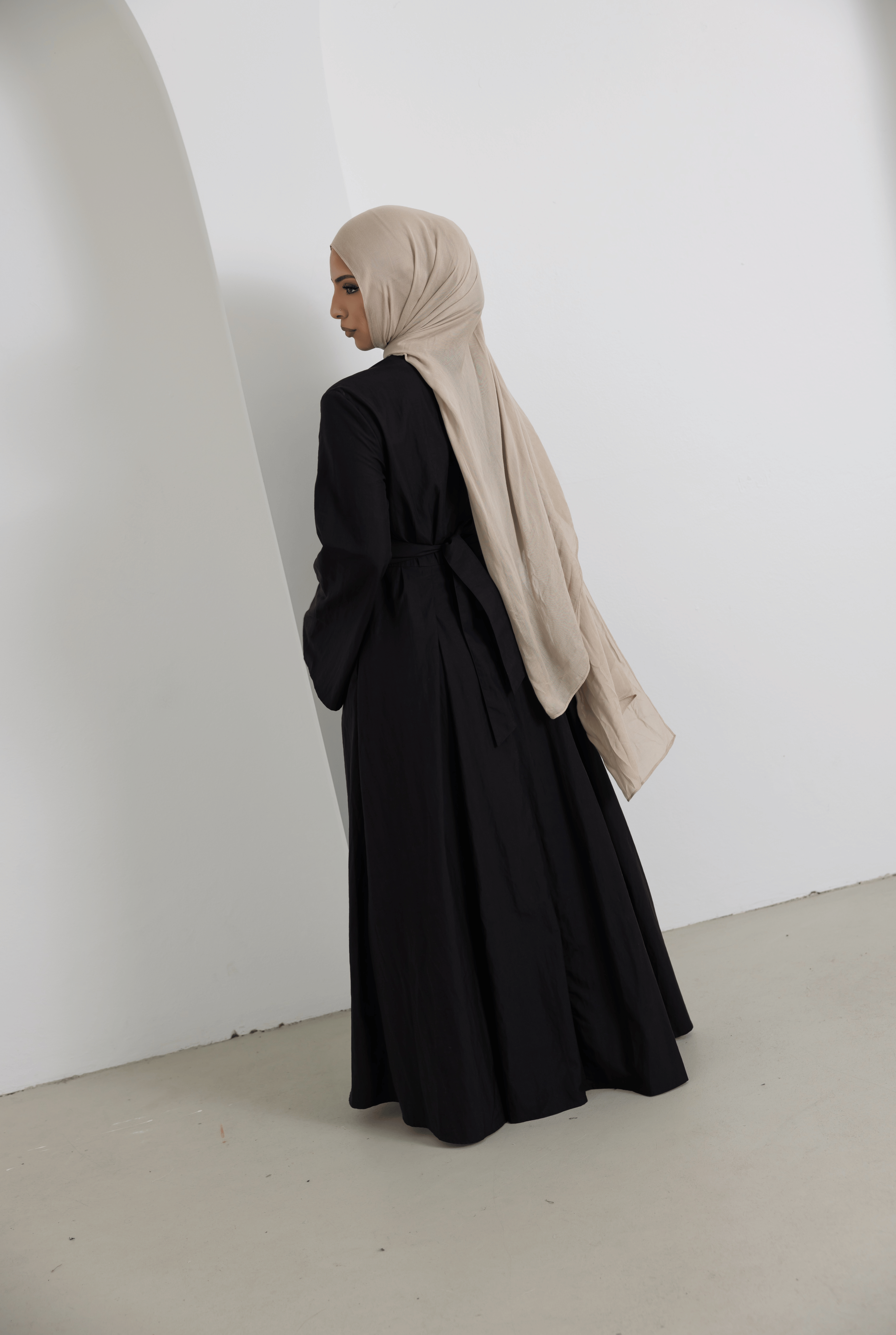 Back view of the Sorelle Belted Dress in black, featuring a full-length modest silhouette, wide sleeves, adjustable waist belt, and soft lyocell-linen blend fabric for elegant everyday wear.