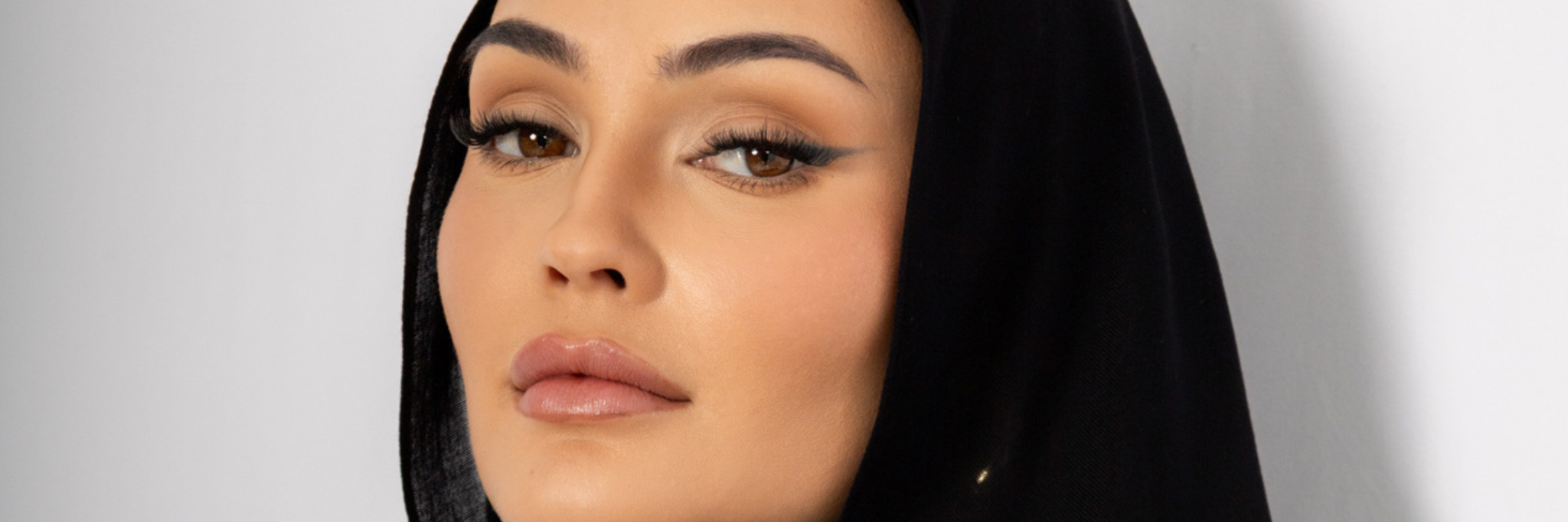 Woman wearing a black chiffon hijab, posing elegantly with a soft drape in a studio setting for modest fashion