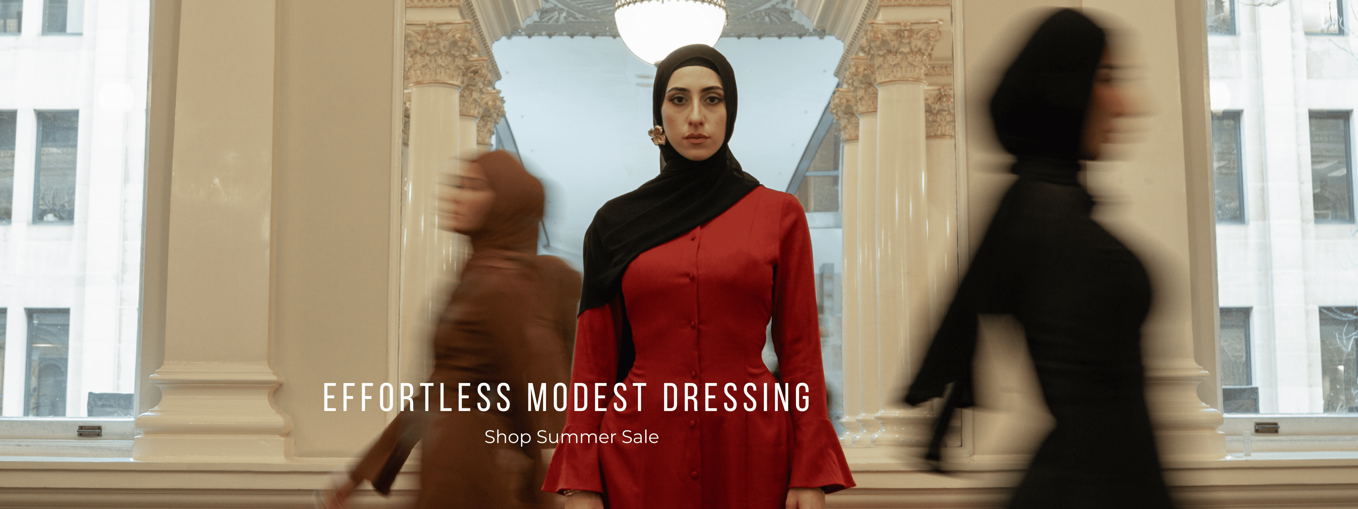 Woman wearing a red modest dress with a black hijab in an elegant interior, representing effortless modest dressing during a summer fashion sale