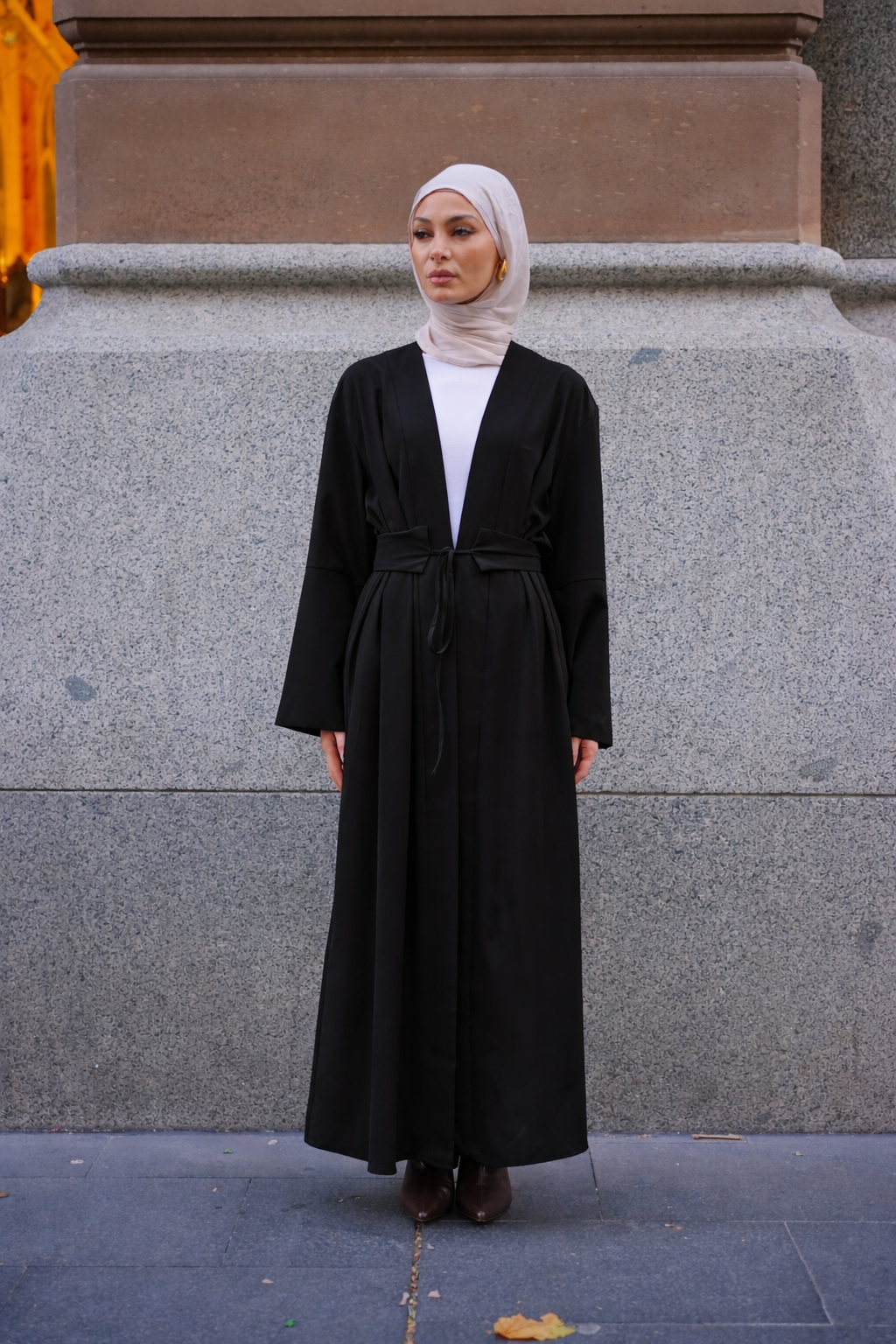 Rowan Belted Abaya in black by Orlena Official, full-length modest dress with a belted waist styled with a hijab in an urban setting