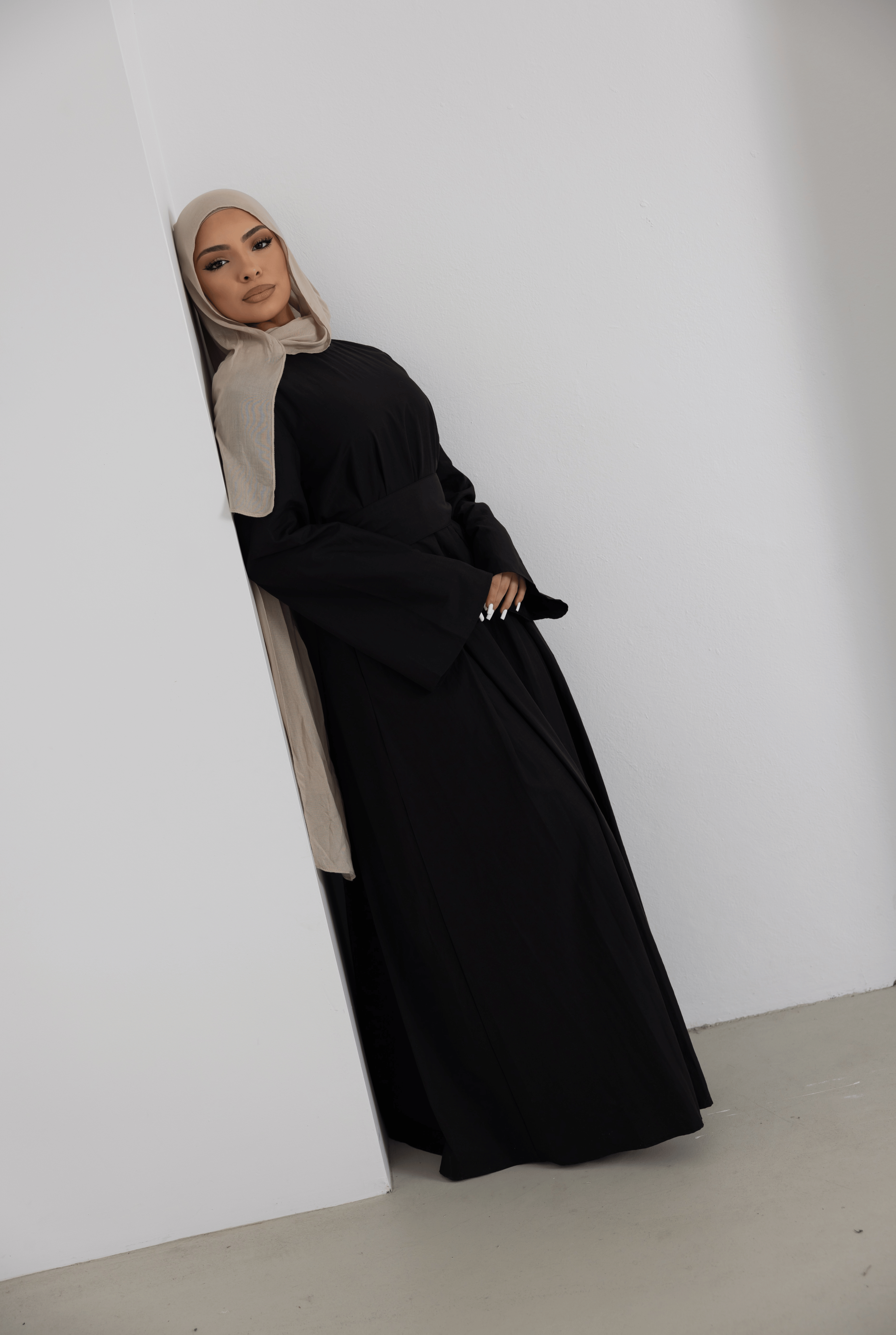 Editorial-style portrait of the Sorelle Belted Dress in black, featuring a flowing full-length silhouette, elegant long sleeves, and a flattering waist belt. Crafted from a breathable lyocell-linen blend, this modest maxi dress combines timeless sophistication, comfort, and effortless elegance.