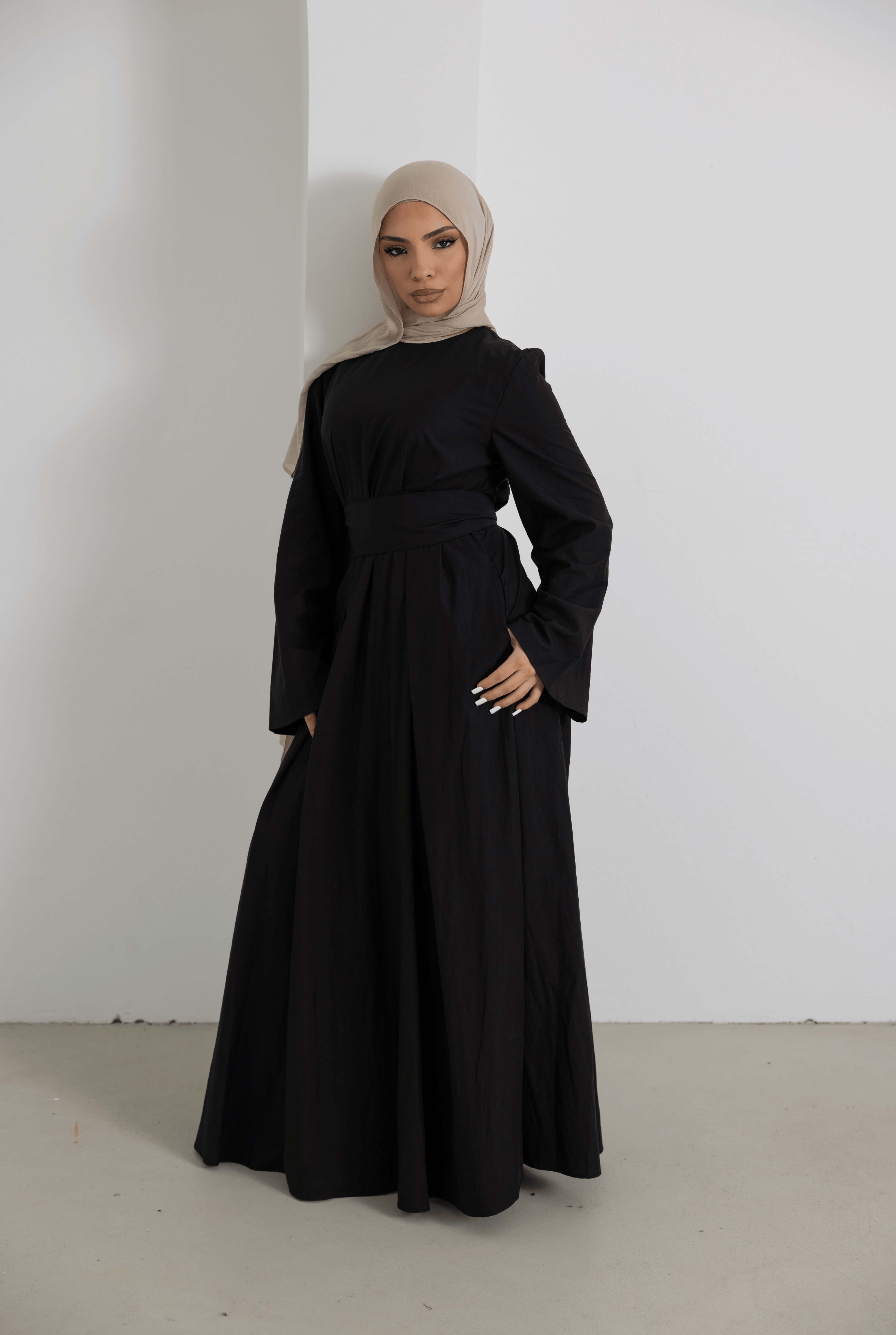 Front standing view of the Sorelle Belted Dress in black, featuring a flattering wide waist belt, elegant long sleeves, and a flowing full-length silhouette. Crafted from a breathable lyocell-linen blend, this modest maxi dress offers timeless sophistication, comfort, and effortless everyday elegance.