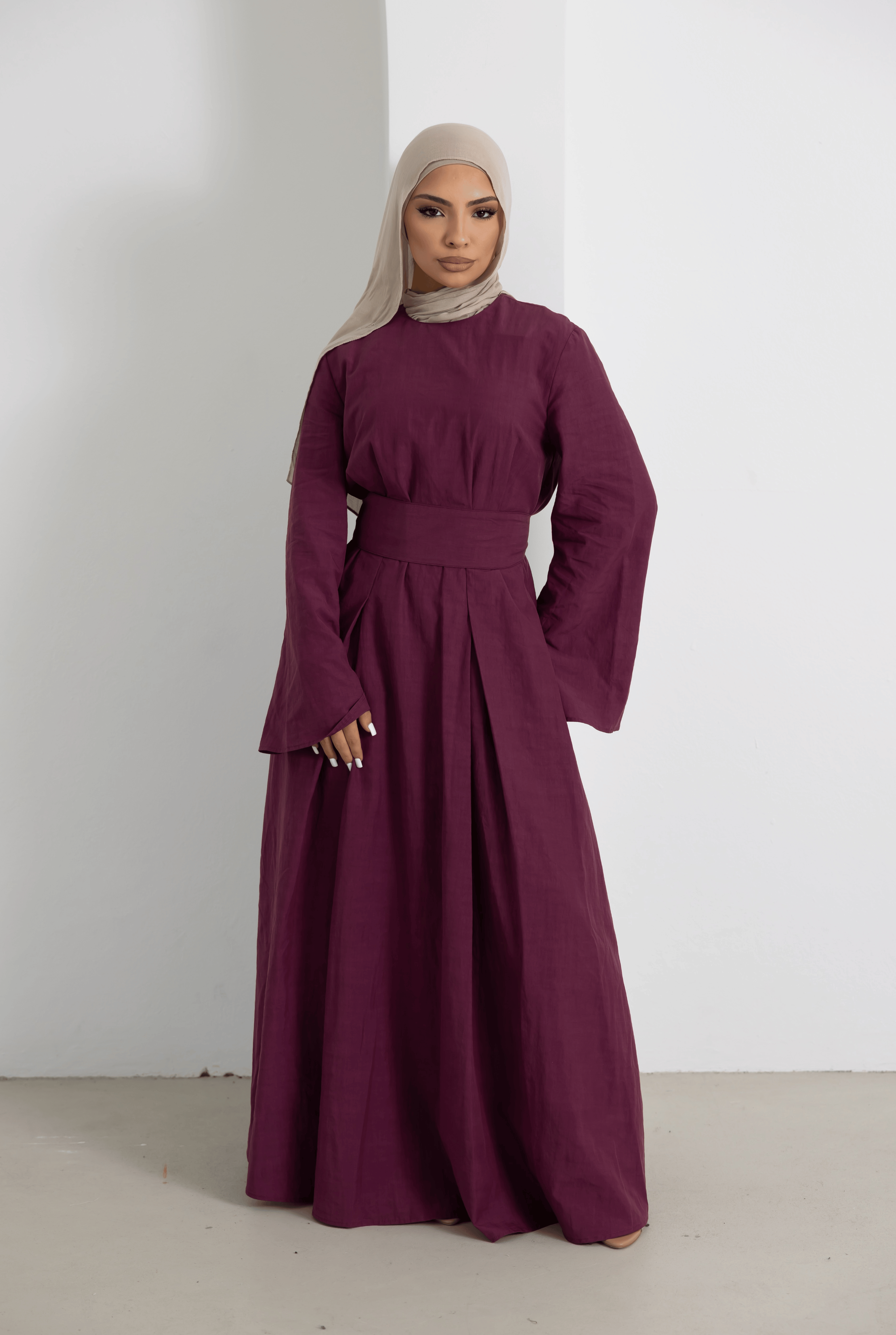 Front view of the Sorelle Belted Dress in plum, featuring a flattering wide waist belt, elegant long sleeves, and a flowing full-length silhouette. Crafted from a breathable lyocell-linen blend, this modest maxi dress offers timeless style, comfort, and effortless sophistication for everyday and occasion wear.