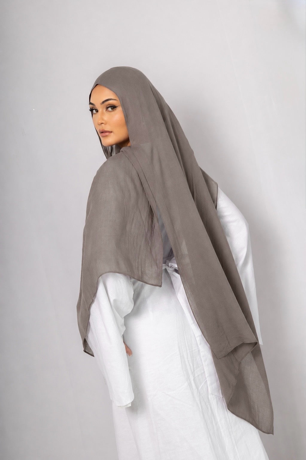 Back view of a model wearing the Stone Taupe modal hijab, highlighting its soft stone taupe shade, lightweight breathable fabric, long elegant drape, and graceful modest styling