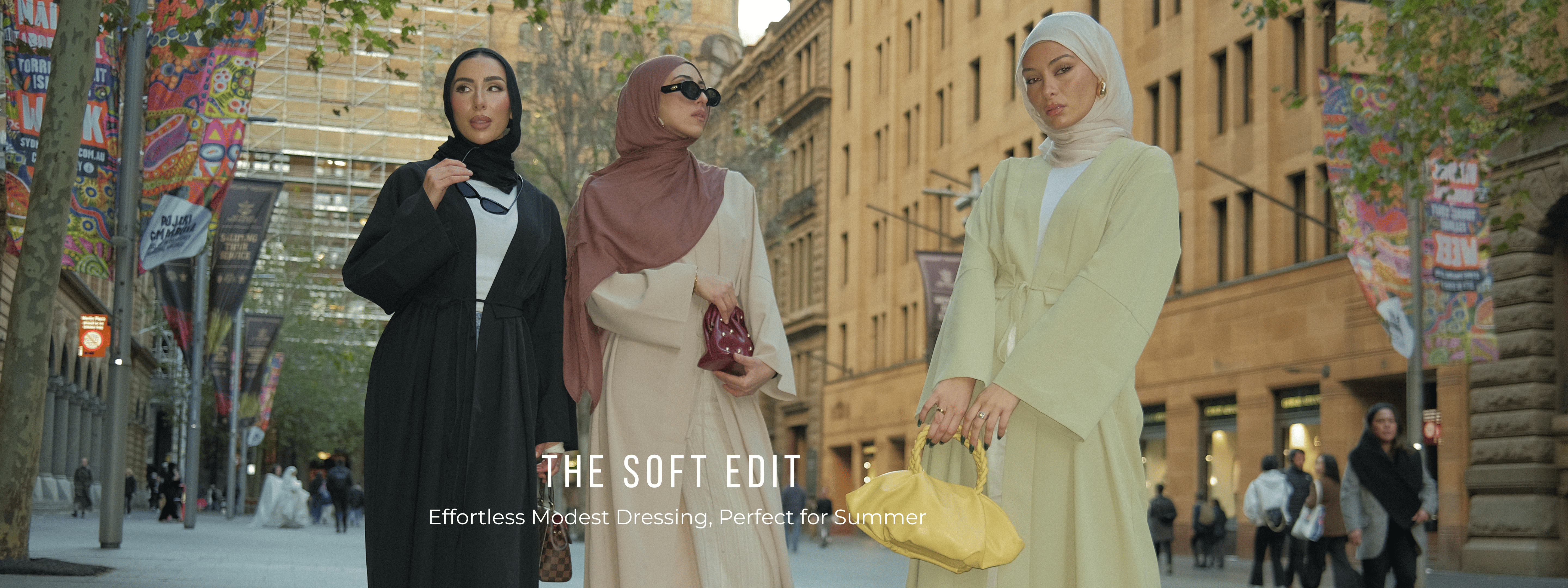 Three women wearing elegant modest summer outfits with hijabs in neutral tones, styled with a yellow handbag, showcasing effortless modest fashion in a city setting
